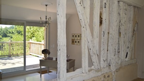 A room with a large sliding glass door leading to a balcony, a chandelier, and a rustic wall with peeling paint. - CHARMING PERIGOURDINE ALONG THE DORDOGNE (Cours-De-Pile)