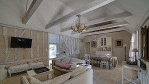 A spacious living room with a high ceiling, exposed beams, a chandelier, a television, and a dining area with a table and chairs. - CHARMING PERIGOURDINE ALONG THE DORDOGNE (Cours-De-Pile)