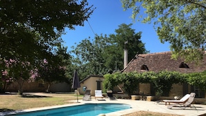 A backyard with a swimming pool, lounge chairs, and a stone building. - CHARMING PERIGOURDINE ALONG THE DORDOGNE (Cours-De-Pile)