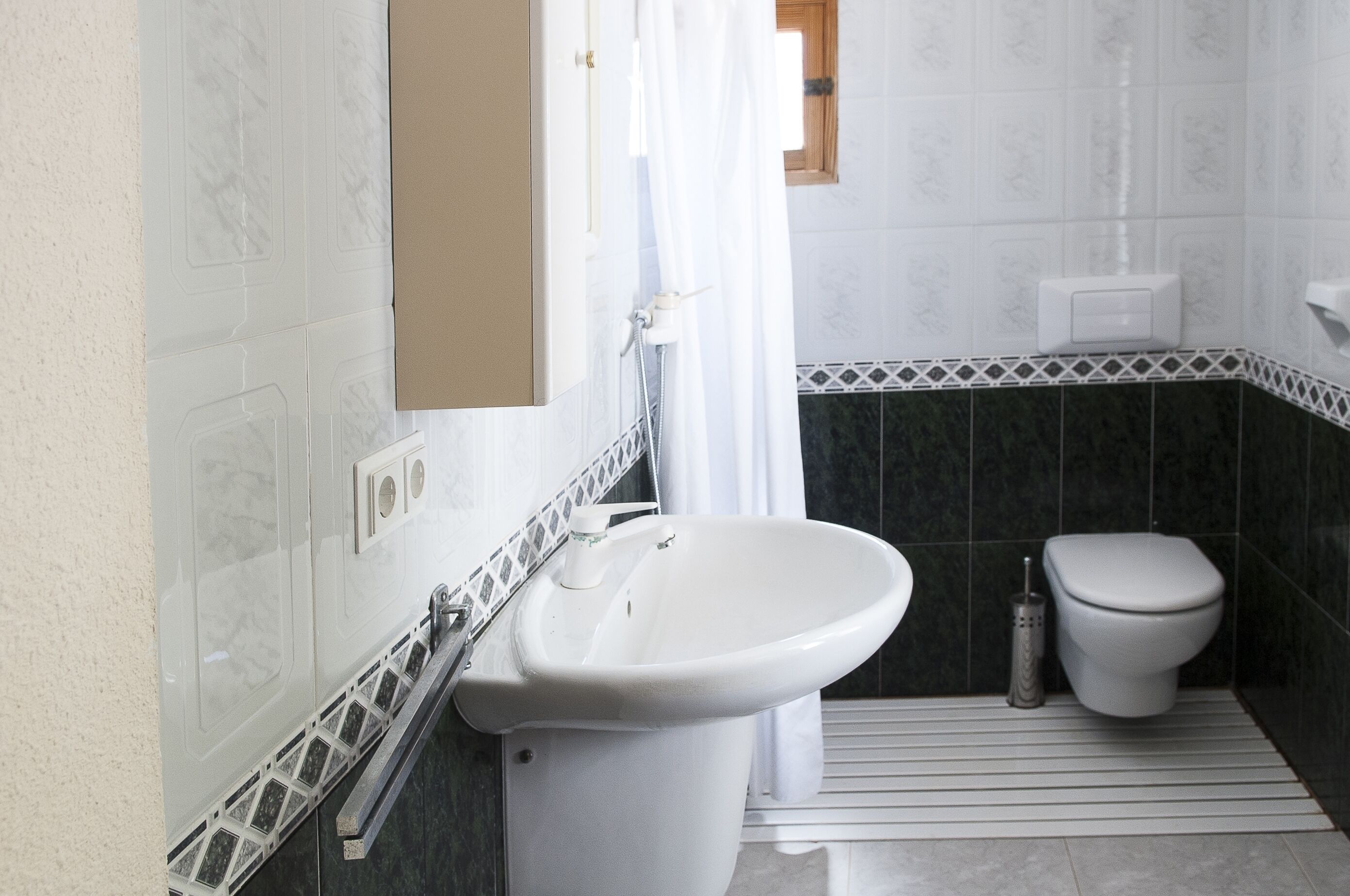 Un bagno con un lavandino bianco, un water e una tenda doccia.