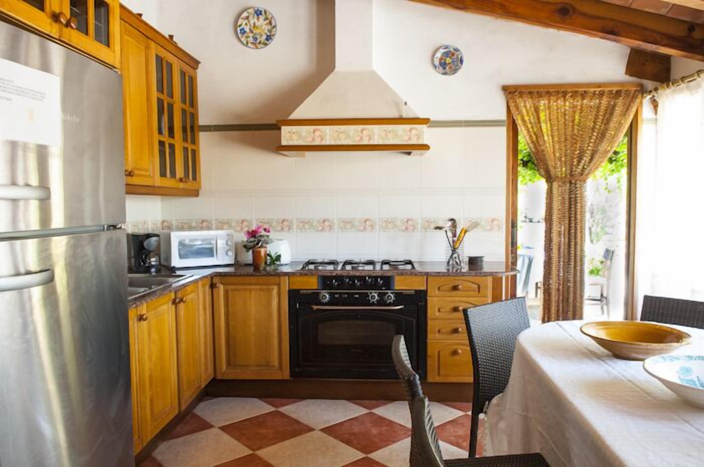 A kitchen with wooden cabinets, a stainless steel refrigerator, a microwave, a stove, and a dining area with a table and chairs.
