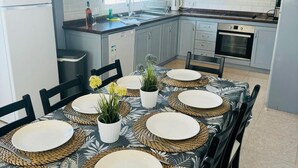 A modern kitchen with grey cabinets, a built-in oven, and a dining area set with a table, chairs, and placemats.