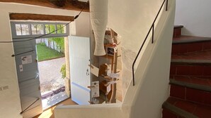 A staircase with a white wall and a wooden beam. There are framed pictures on the wall and a hanging light fixture. - houses / villas - 4 rooms - 6 persons (L'isle-Sur-La-Sorgue)