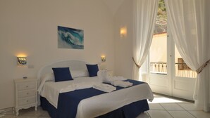 A bedroom with a bed, white nightstands, a painting, and a view of a balcony. - L'Ancora - Bright Sea front, Self Catering Apartment (Minori)