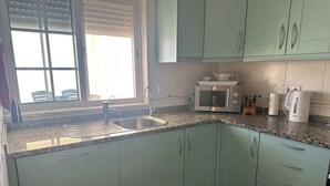A kitchen with a sink, a microwave, and cabinets. - Impressive Villa in Ferragudo, with Private Pool, Air Con, Garden & Fibre WiFi. (lagoa)