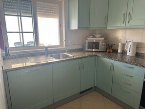 A kitchen with a sink, a microwave, and cabinets. - Impressive Villa in Ferragudo, with Private Pool, Air Con, Garden & Fibre WiFi. (lagoa)