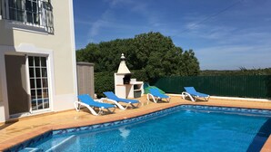 A swimming pool with blue lounge chairs and a small gazebo. - Impressive Villa in Ferragudo, with Private Pool, Air Con, Garden & Fibre WiFi. (lagoa)