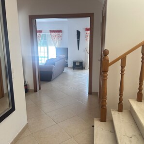 A hallway leading to a living room with a sofa, a television, and a small table.