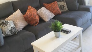 A modern living room with a grey sofa, patterned cushions, a white coffee table, and a wall-mounted painting. - Puerto Marina 2 bedroom 2 bath apartment in Los Alcazares (Murcia)