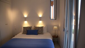 A bedroom with a bed, two wall-mounted lights, a window, and a nightstand. - Villa in Kamilari, Heraklion and surroundings sea and mountain view and private swimming pool (Kamilari)