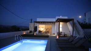 A modern outdoor pool area with lounge chairs and a well-lit patio. - Villa in Kamilari, Heraklion and surroundings sea and mountain view and private swimming pool (Kamilari)