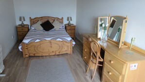Une chambre à coucher avec un lit en bois, des tables de chevet, une commode, un miroir et une chaise.