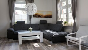 Un salon moderne avec un canapé d’angle, une table basse blanche et un fauteuil blanc.