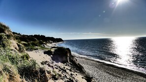 A coastal landscape with a sandy beach, rocky cliffs, and a clear sky. - Charming, family-friendly vacation home close to the beach with a beautiful sun terrace (Dranske / Bakenberg)