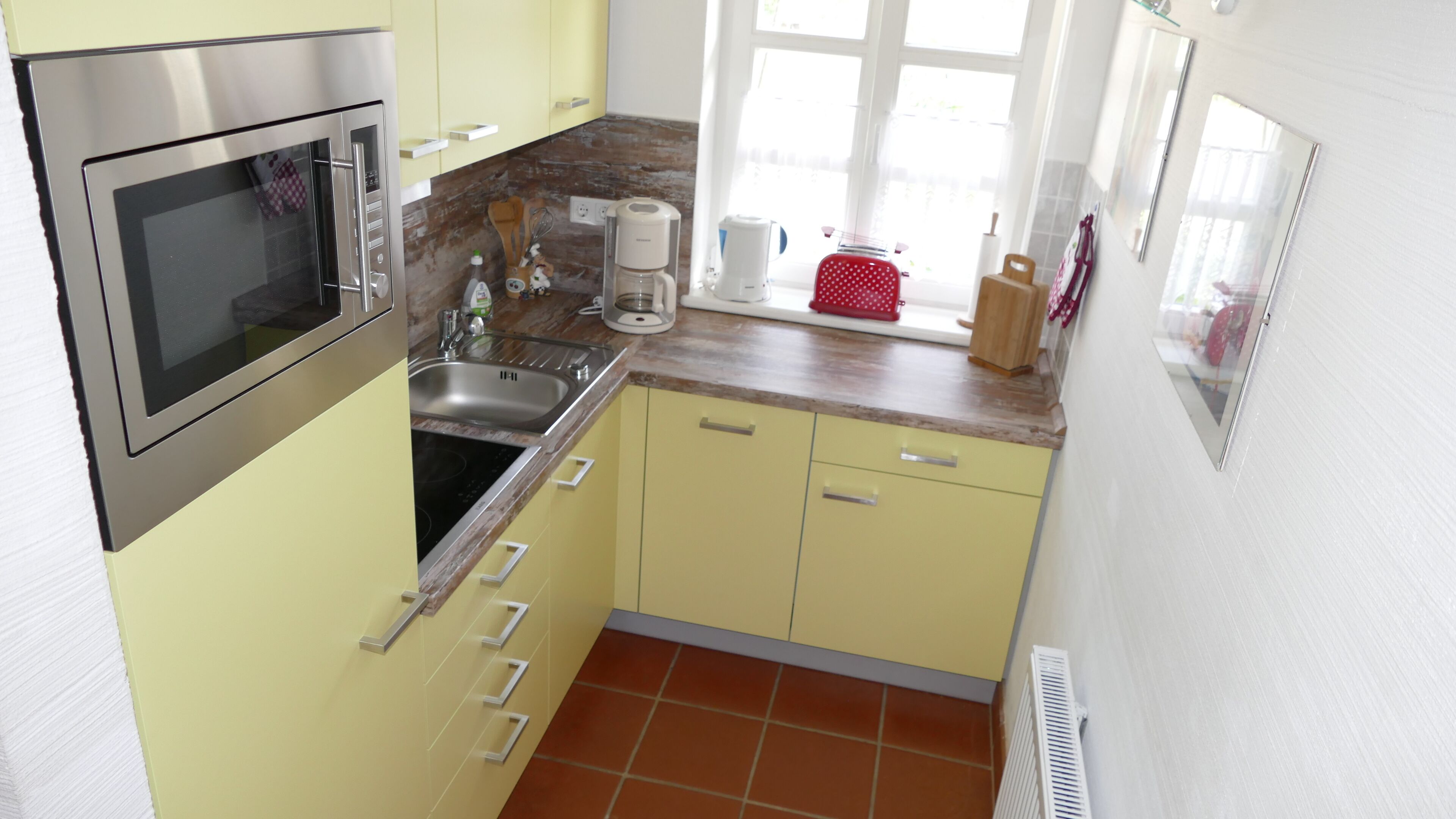 Een kleine keuken met een inbouwoven, een spoelbak en een koffiezetapparaat.