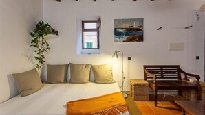 A bedroom with a bed, a window, a painting, a plant, and a bench. - Casa Anita - Village House With Charming (Ses salines)