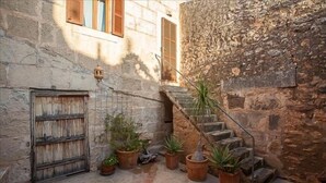 A narrow courtyard with a stone wall, a wooden door, and a staircase leading to an upper level. - Casa Anita - Village House With Charming (Ses salines)