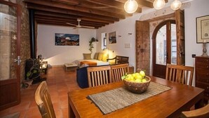 A dining area with a wooden table, chairs, and a bowl of fruit. There is a ceiling fan and pendant lights above the table. - Casa Anita - Village House With Charming (Ses salines)