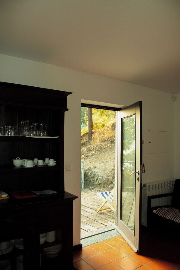 A room with a dark wooden cabinet, a glass door leading outside, and a bed with striped bedding. - Casa de Gondomil for 4 people (Alpendorada e Matos)