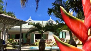 A resort with a pool, palm trees, and a covered patio area.