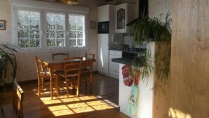 A kitchen with wooden cabinets, a dining table with chairs, and a window with frosted glass. - country holiday home - 7 rooms - 5/6 persons (Labrousse)