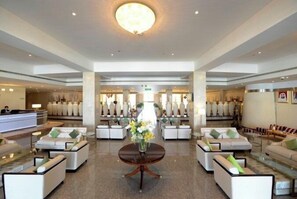 A spacious lobby with a reception desk, seating areas, and decorative vases.