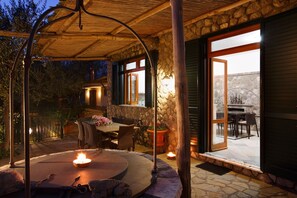 An outdoor patio area with a stone fireplace, a round table, and chairs. - Villa Luisa, splendid panoramic villa overlooking Capri (MASSA LUBRENSE)