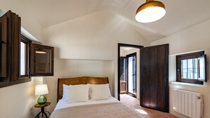 A bedroom with a large bed, a bedside lamp, a radiator, and a window.