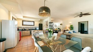 A modern kitchen with a dining area, a ceiling fan, and a staircase leading to an upper level.