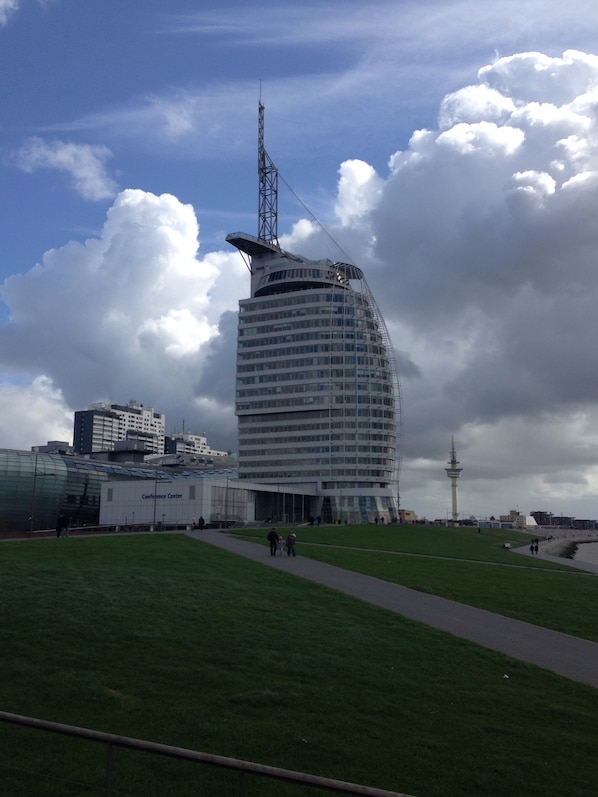 A modern building with a curved facade, a tower, and a walkway leading to it.