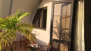 Un balcone con tavolo e sedie, una pianta in vaso e una porta scorrevole in vetro.