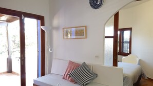 Una habitación con un sofá blanco, un cuadro en la pared y una ventana con persianas.