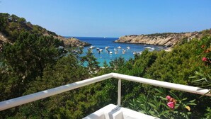 Vista costera con barcos, vegetación y cielo despejado.