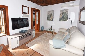 A living room with a TV, sofa, coffee table, and artwork on the walls.