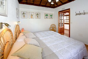 A bedroom with a bed, a chair, and a door leading to another room.