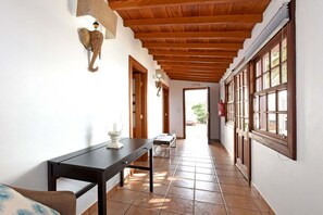 A hallway with a wooden ceiling, a table with a candle, and a bench.