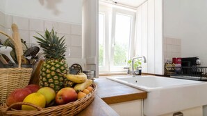 Eine Küche mit einer Holzausziehtafel, einem weißen Spülbecken und einem Fenster mit Blick auf Grün.