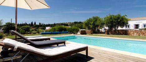 Una piscina al aire libre, sillones reclinables de piscina