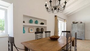 Ein Essbereich mit einem Holztisch, Stühlen, einer Chandelier und Regalen mit Dekoration.