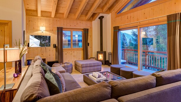 A cozy wooden interior with a sofa, ottoman, and a fireplace.