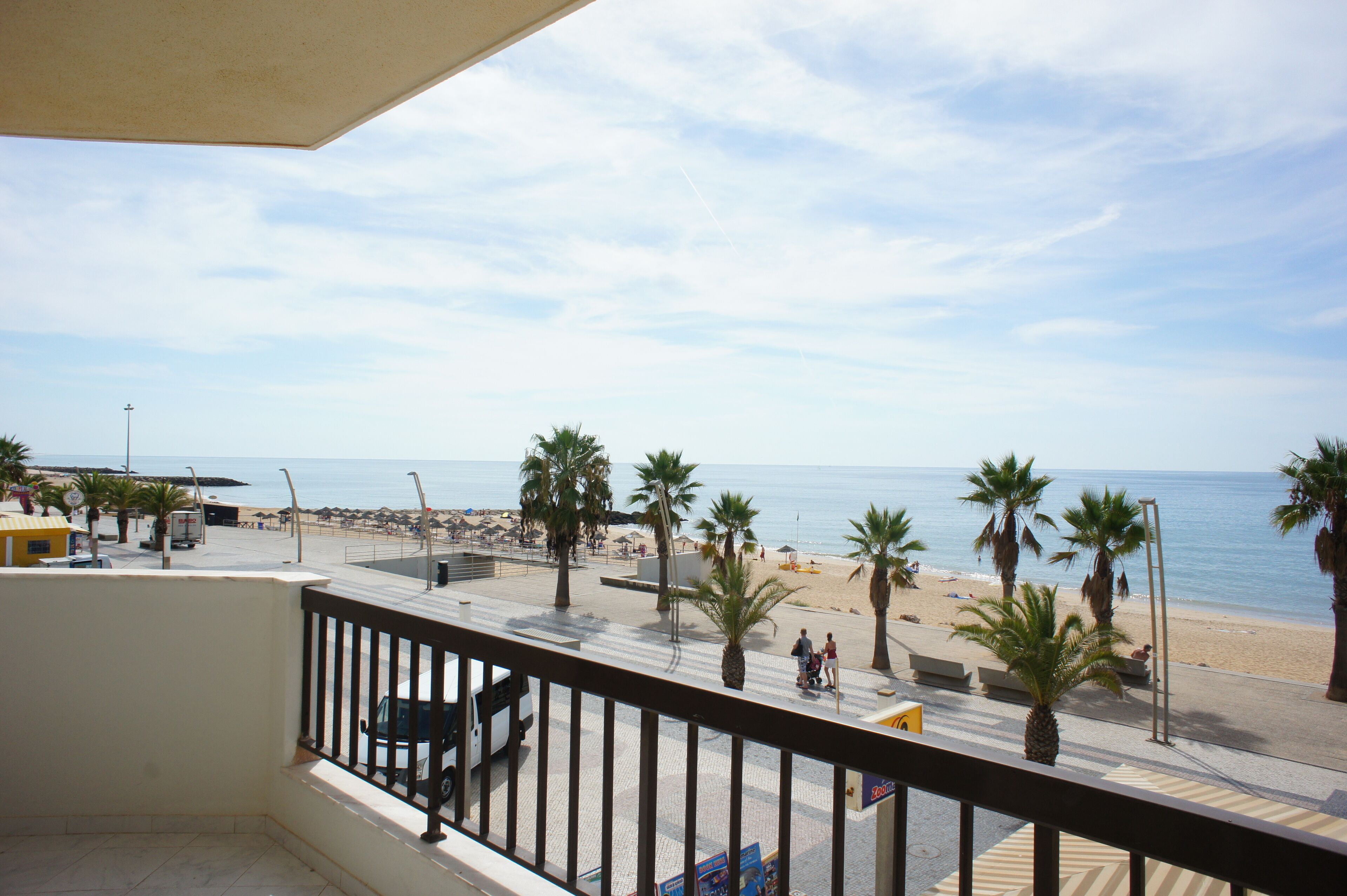 A balcony with a view of a beach, palm trees, and the sea.