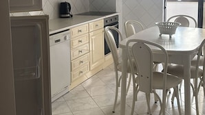 Una cocina con armarios color crema, una estufa y una mesa de comedor con sillas.