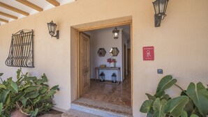 A hotel entrance with a wooden door, a small table with a vase of flowers, and a sign indicating the room number.