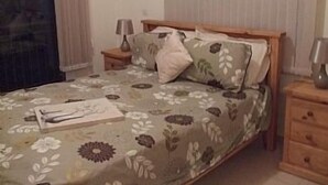 A bedroom with a floral bedspread, a wooden headboard, a bedside table with a lamp, and a nightstand. - Private Pool, Private Location, Free Wifi, All Day Sunbathing in private garden (Alethriko)