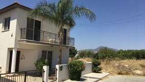 A two-story building with a balcony, a gate, and a palm tree. - Private Pool, Private Location, Free Wifi, All Day Sunbathing in private garden (Alethriko)