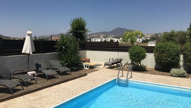 A rooftop pool area with lounge chairs, a small table, and a white umbrella. - Private Pool, Private Location, Free Wifi, All Day Sunbathing in private garden (Alethriko)
