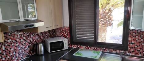 A kitchen with a microwave, stove, and sink.