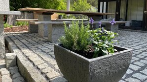 En innergård med en stenkruka, en bänk och en byggnad med ett klinkergolv.