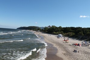 Una playa con olas, gente y edificios al fondo.