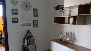 A room with a bookshelf, wall-mounted decorations, and a small ship model.